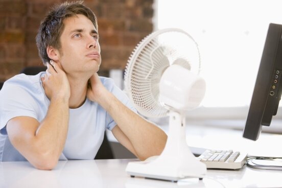 Biure karšta, ventiliatorius, nuo karščio kenčiantis darbuotojas
